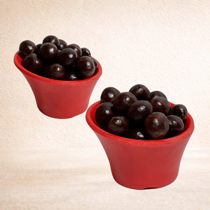 Two red cups filled with paan shot pan shot pan flavor candy on a beige background